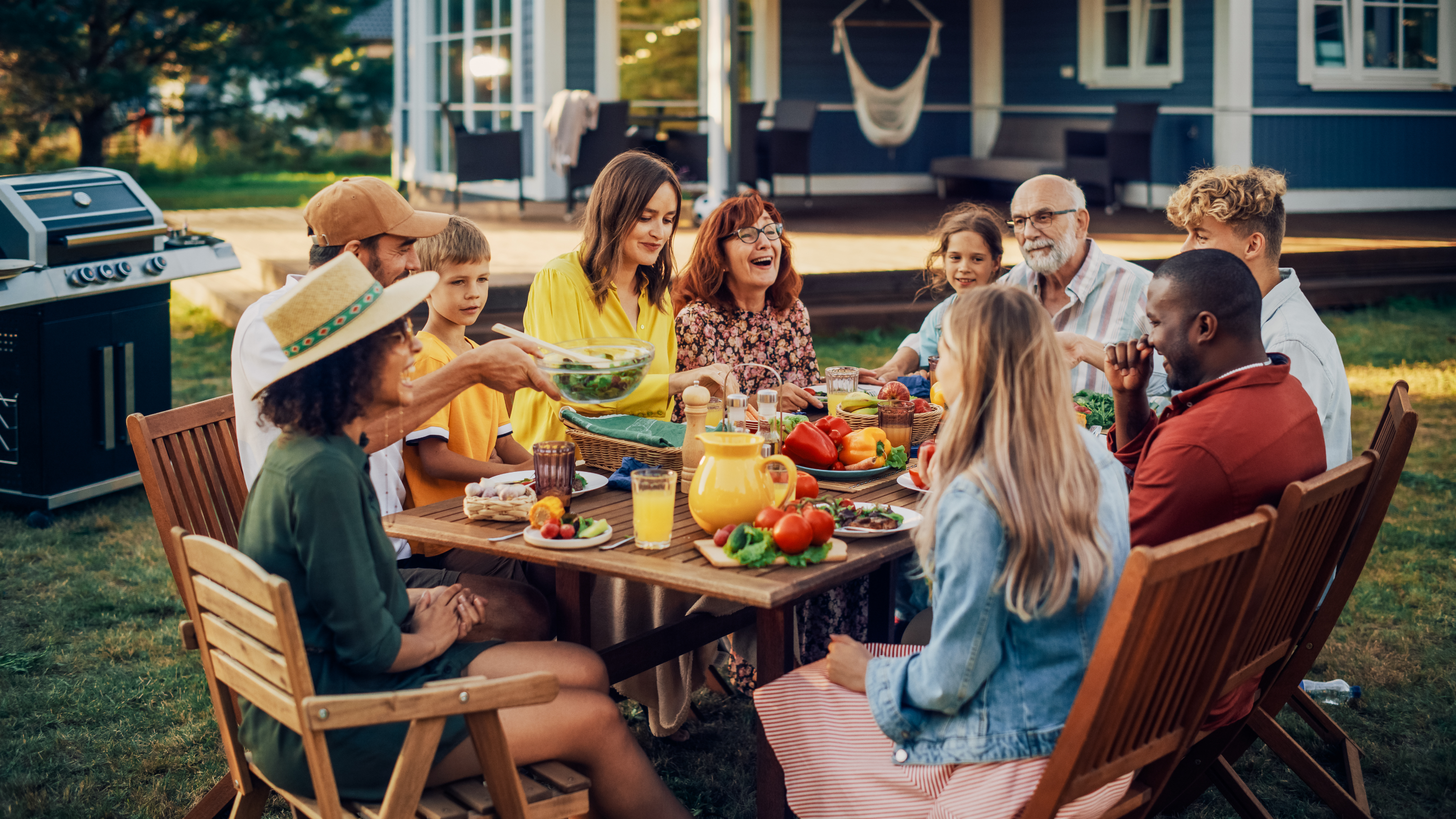 A group of family and friends having an outdoor dinner in their backyard.